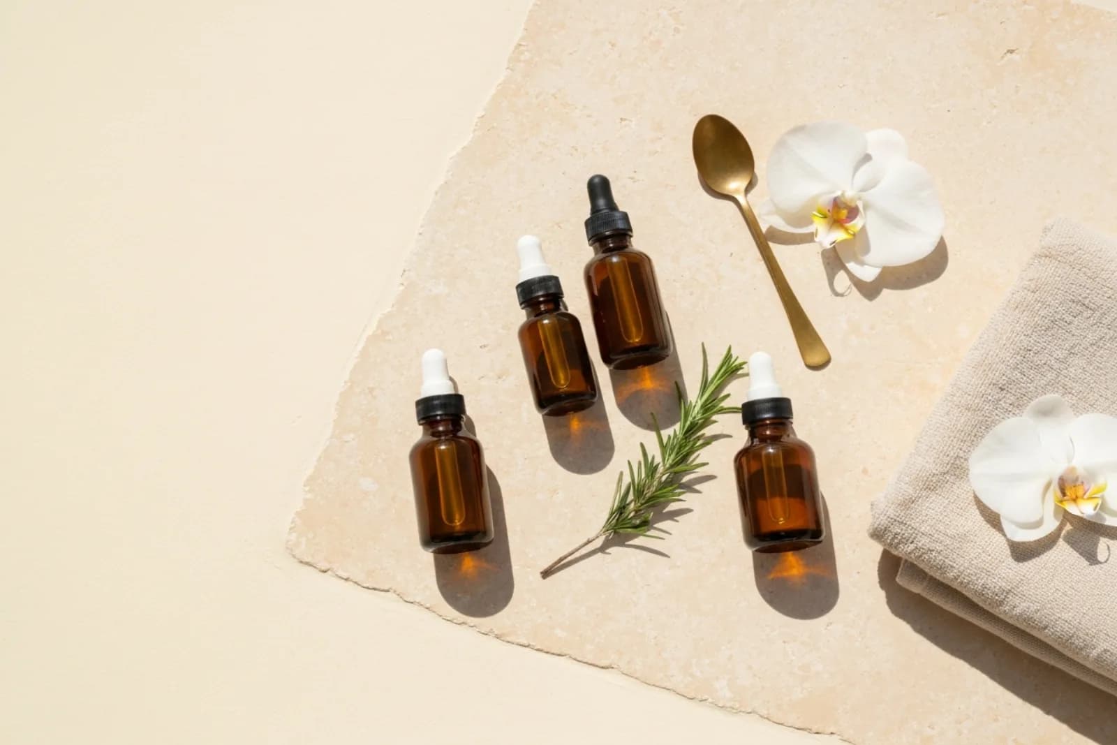 Natural beauty treatments: amber dropper bottles, rosemary, orchids, and a towel on stone for St Julian's, Malta.