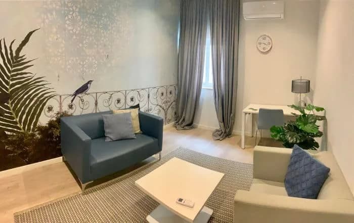 Comforting room with a light sofa, bookshelf, and window, ideal for mental health support in Gwardamanga, Malta.