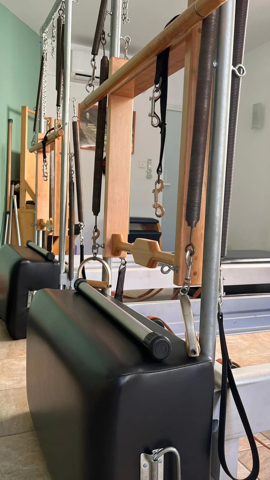 Bright Pilates & yoga studio in Attard, Malta, with a white reformer, arched window, and hanging plants.